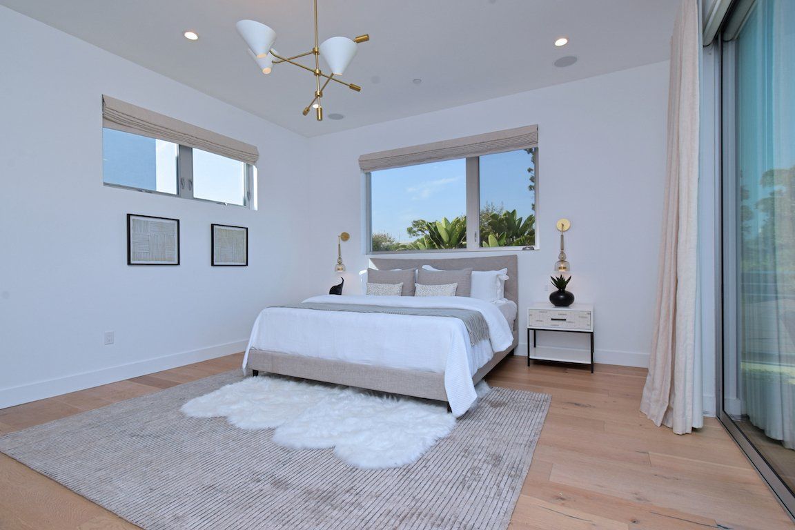 A bedroom with a bed , nightstand , rug and windows.