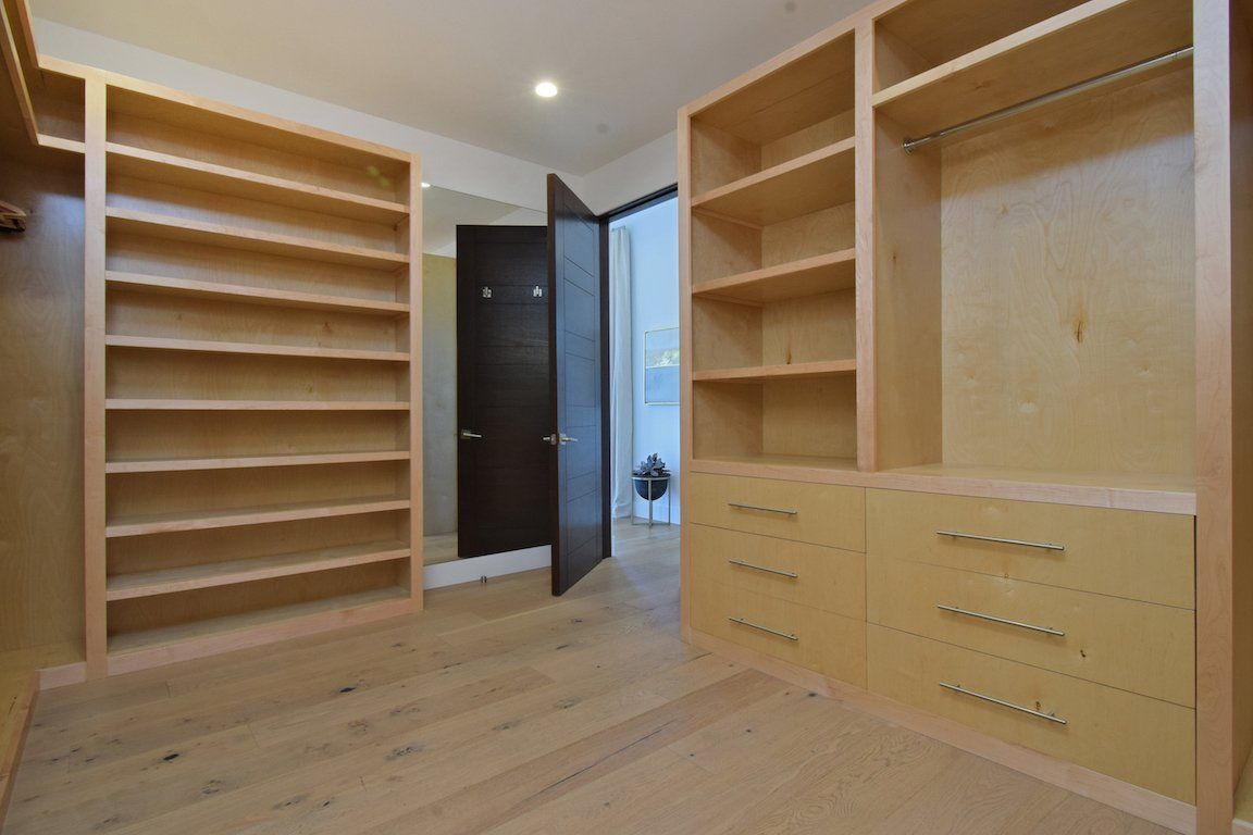 A walk in closet with lots of shelves and drawers