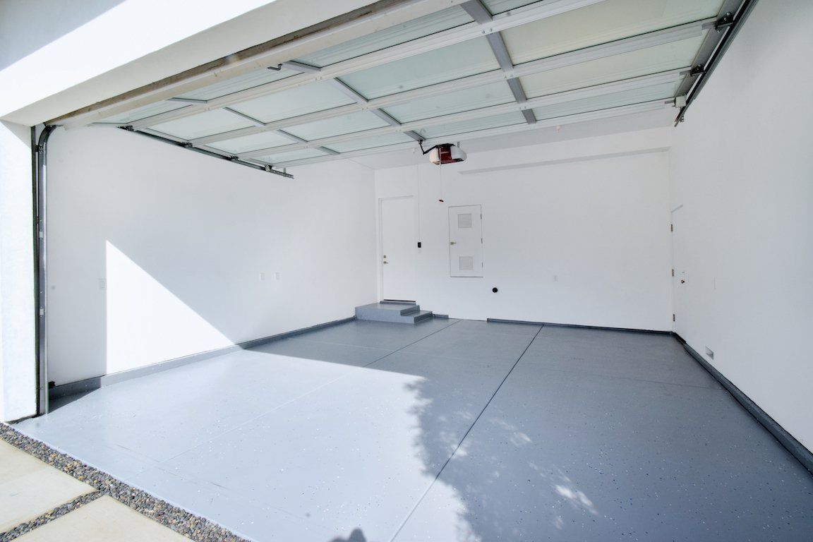 An empty garage with a gray floor and white walls