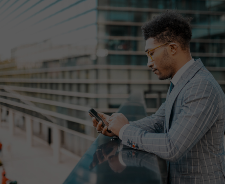A man in a suit and tie is looking at his cell phone.