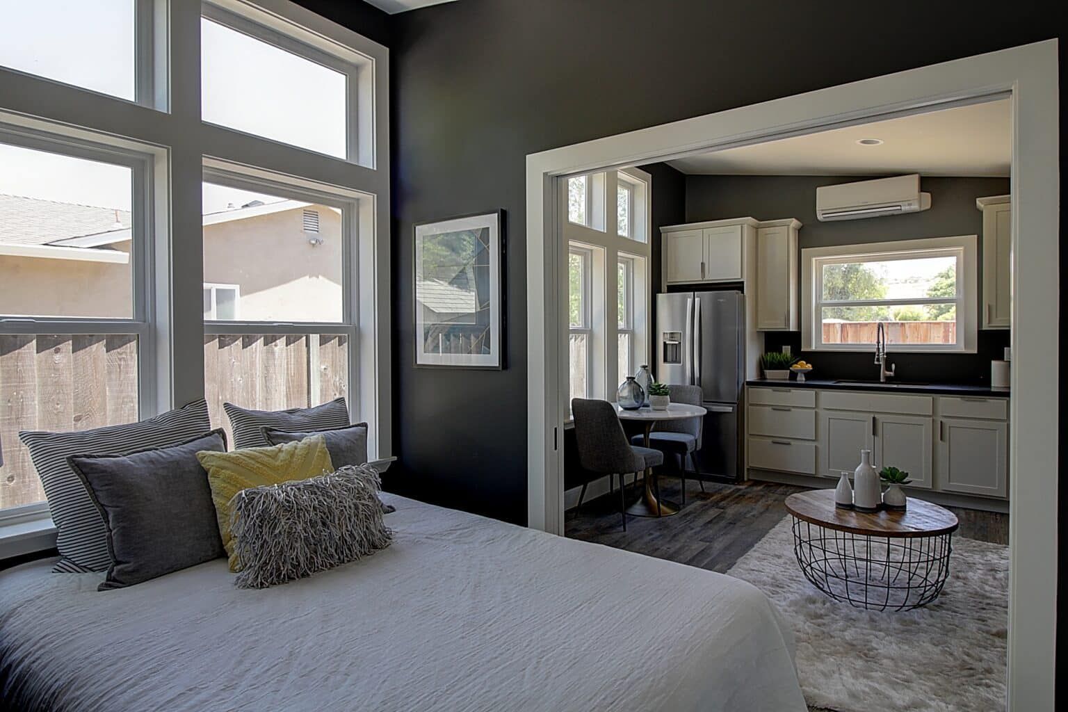 A bedroom with a bed and a kitchen in the background.