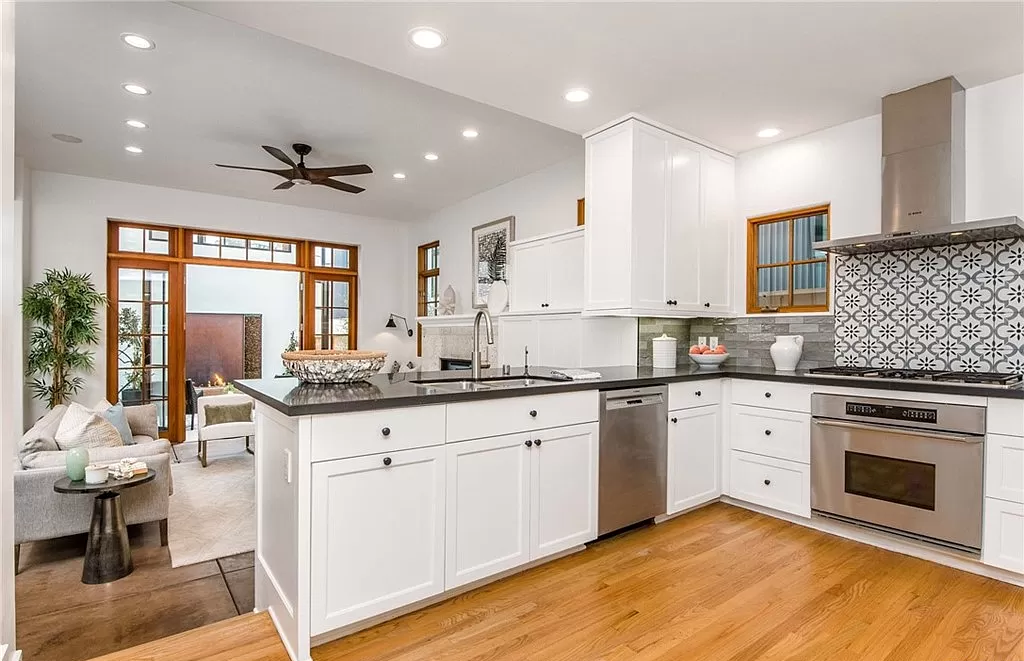 A kitchen with white cabinets , stainless steel appliances , and hardwood floors.