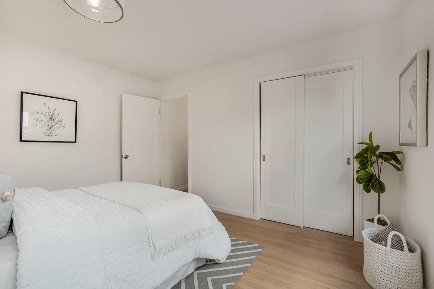 A bedroom with a bed , closet and a plant.