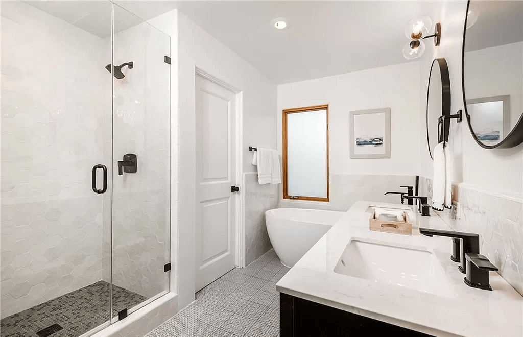 A bathroom with a tub , sink , shower and mirror.