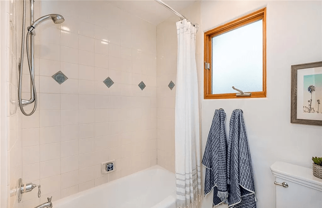 A bathroom with a bathtub , toilet , shower and window.