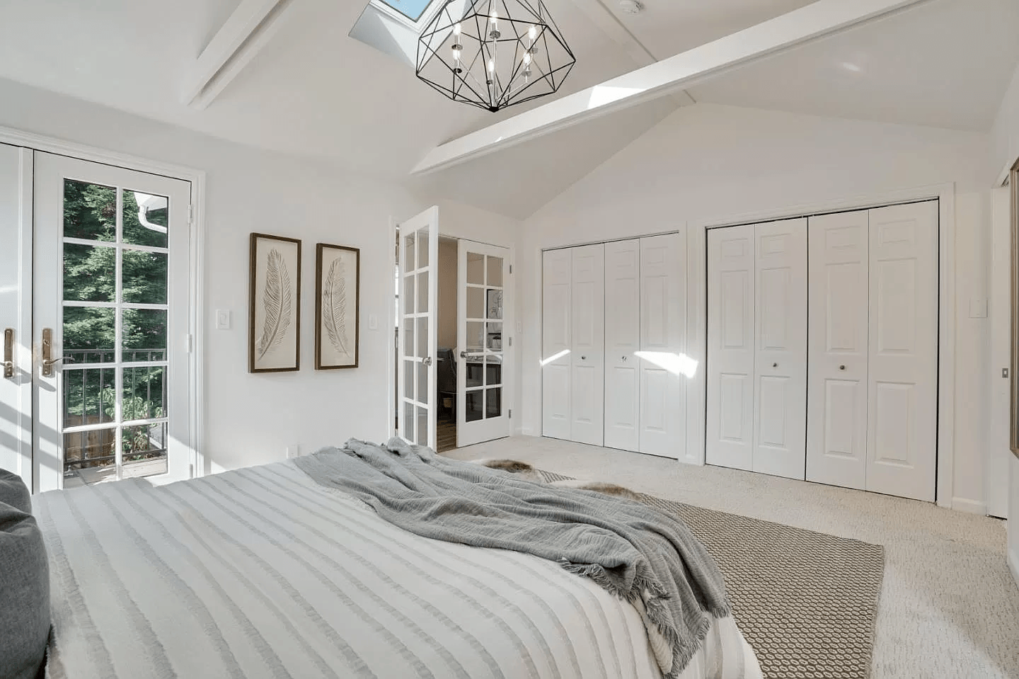 A bedroom with a large bed , lots of closets and a skylight.