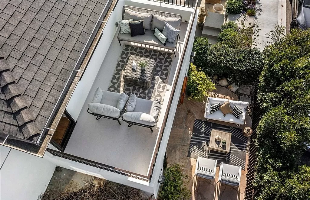 An aerial view of a rooftop patio with a couch , table and chairs.