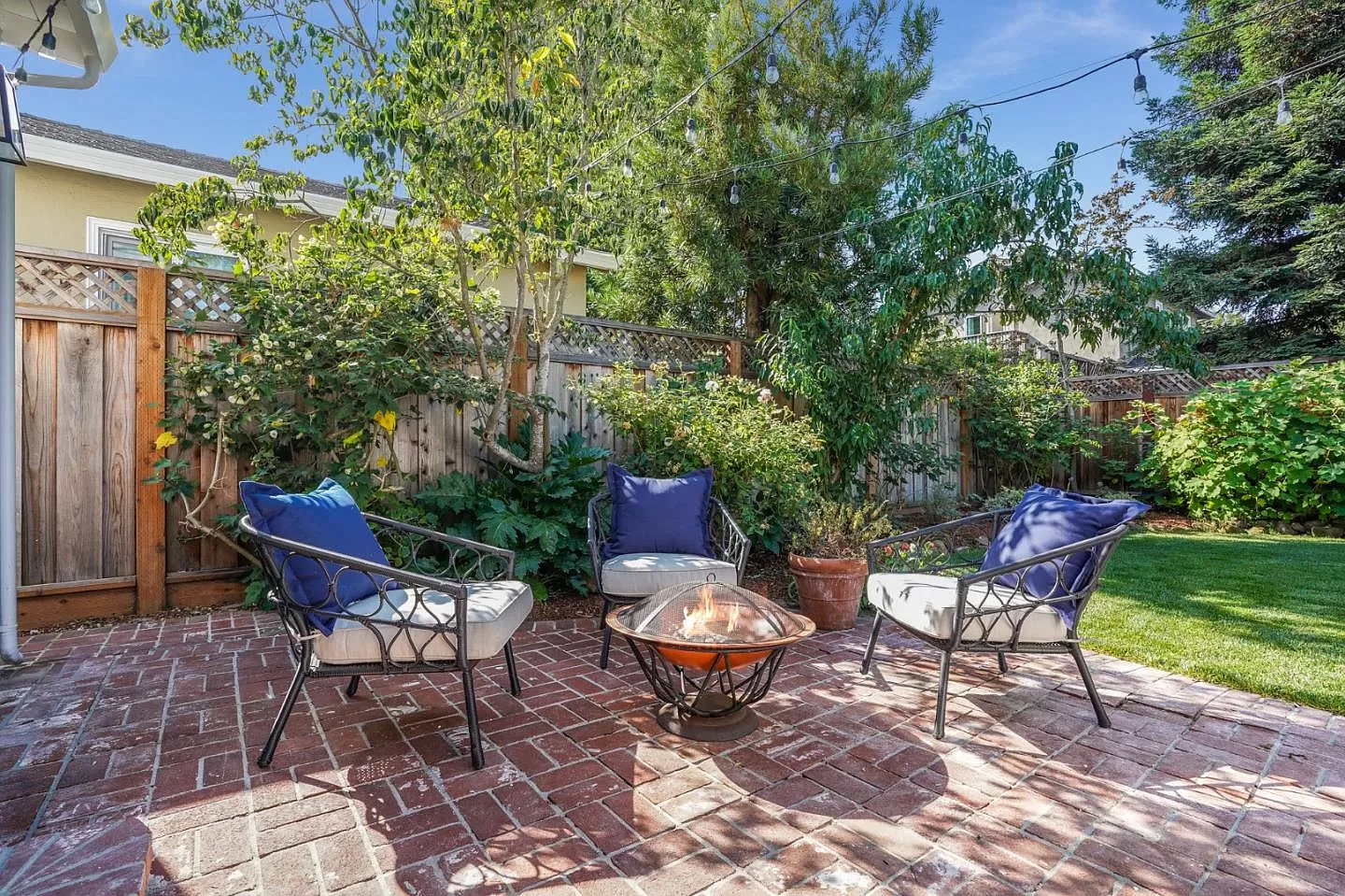 There is a fire pit on the patio with chairs and a table.