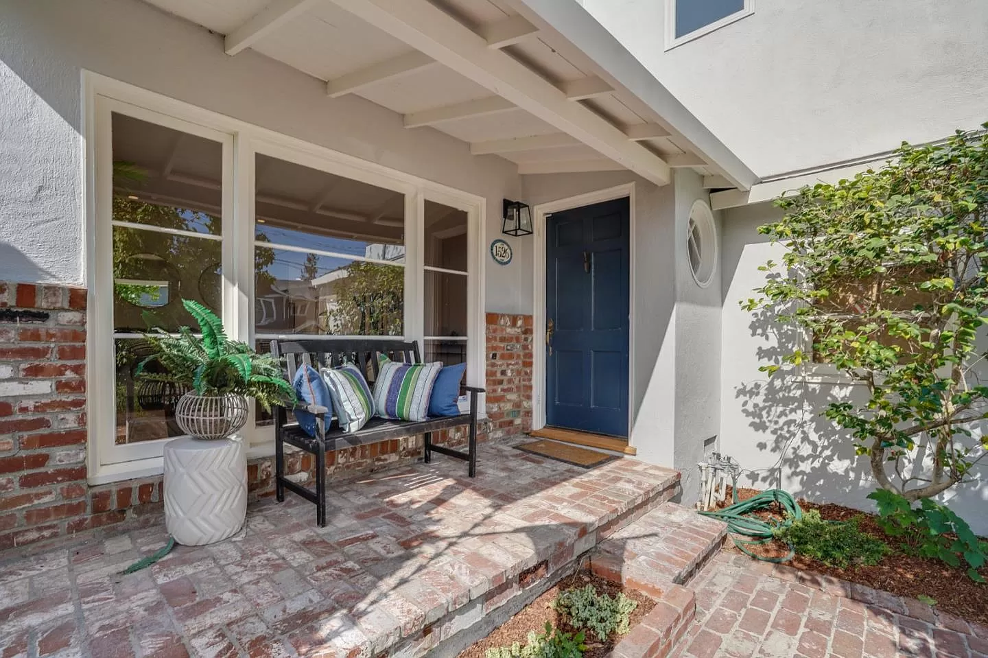 The front porch of a house with a bench and a blue door.