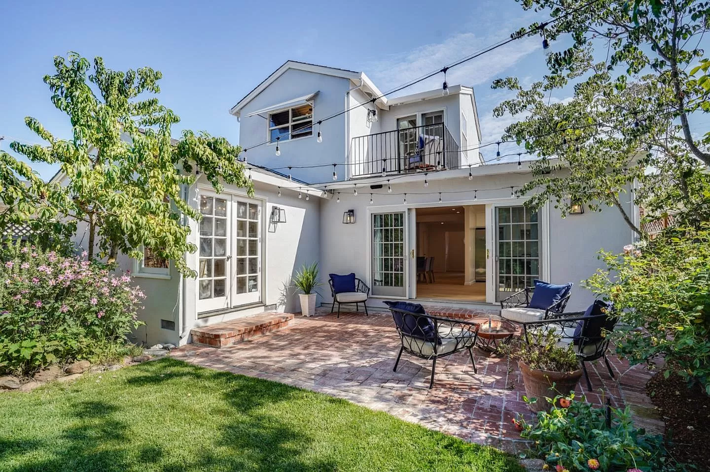 A white house with a patio and chairs in front of it.