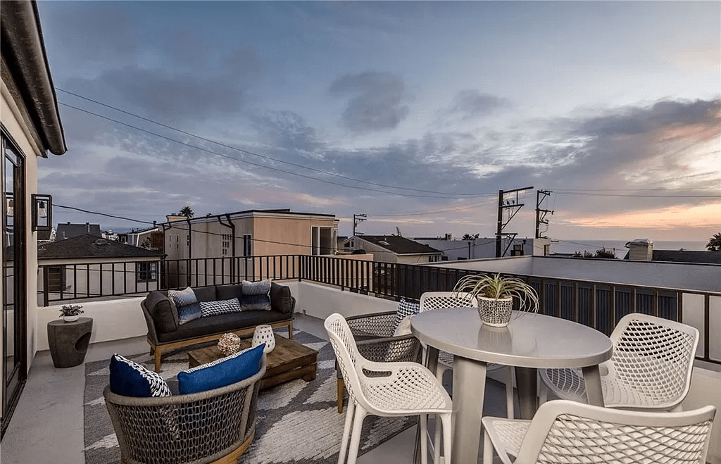A rooftop deck with a table and chairs and a couch.