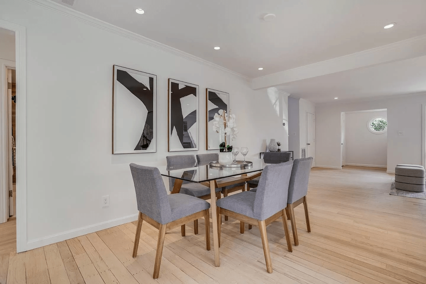 A dining room with a table and chairs and paintings on the wall.