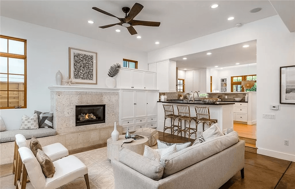 A living room with a couch , chairs , a fireplace and a ceiling fan.