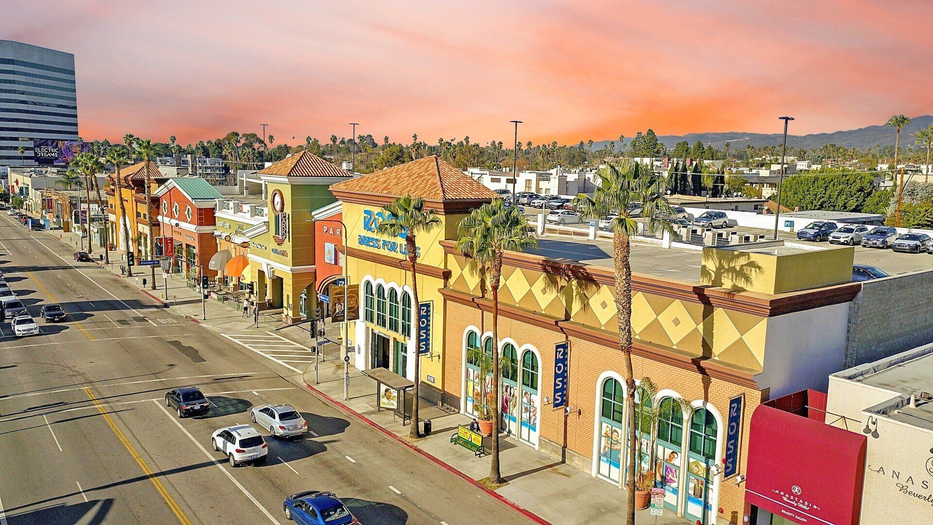 An aerial view of a city street with a lot of buildings and cars driving down it.