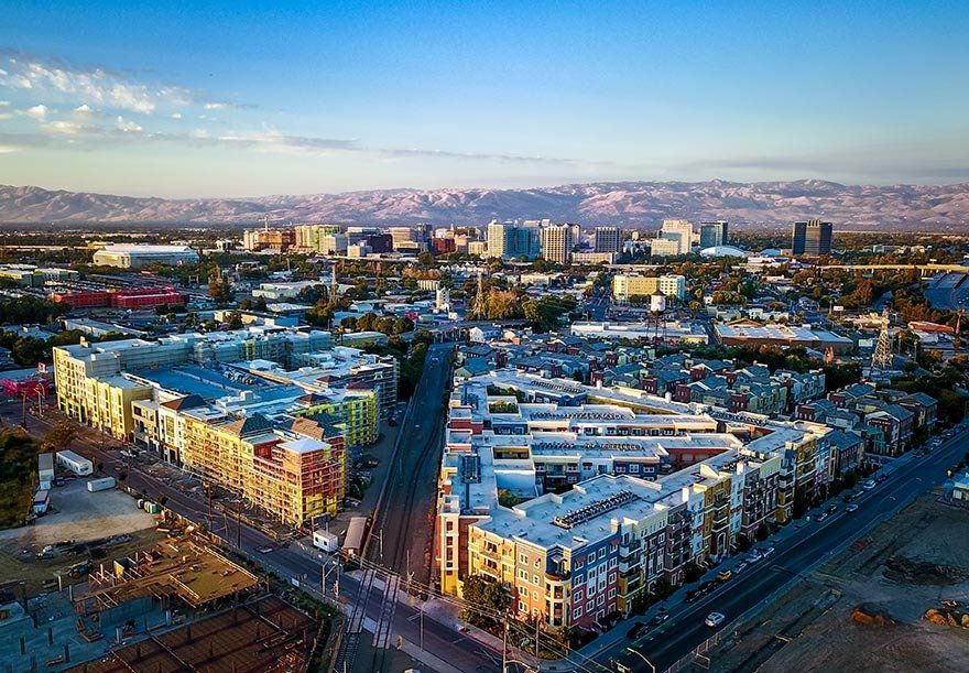 An aerial view of a city with a lot of buildings and mountains in the background.