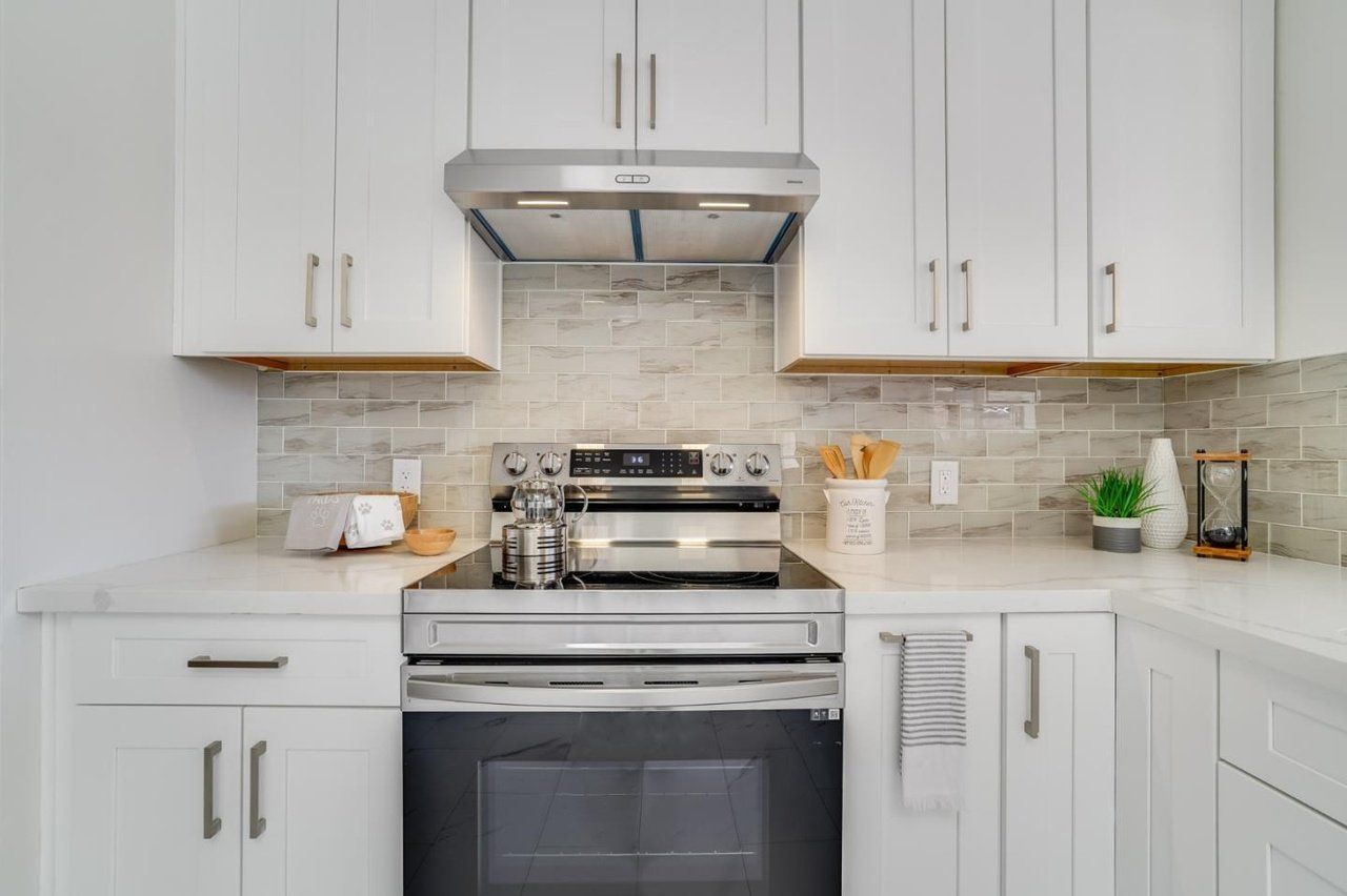 A kitchen with white cabinets , a stove , oven and microwave.