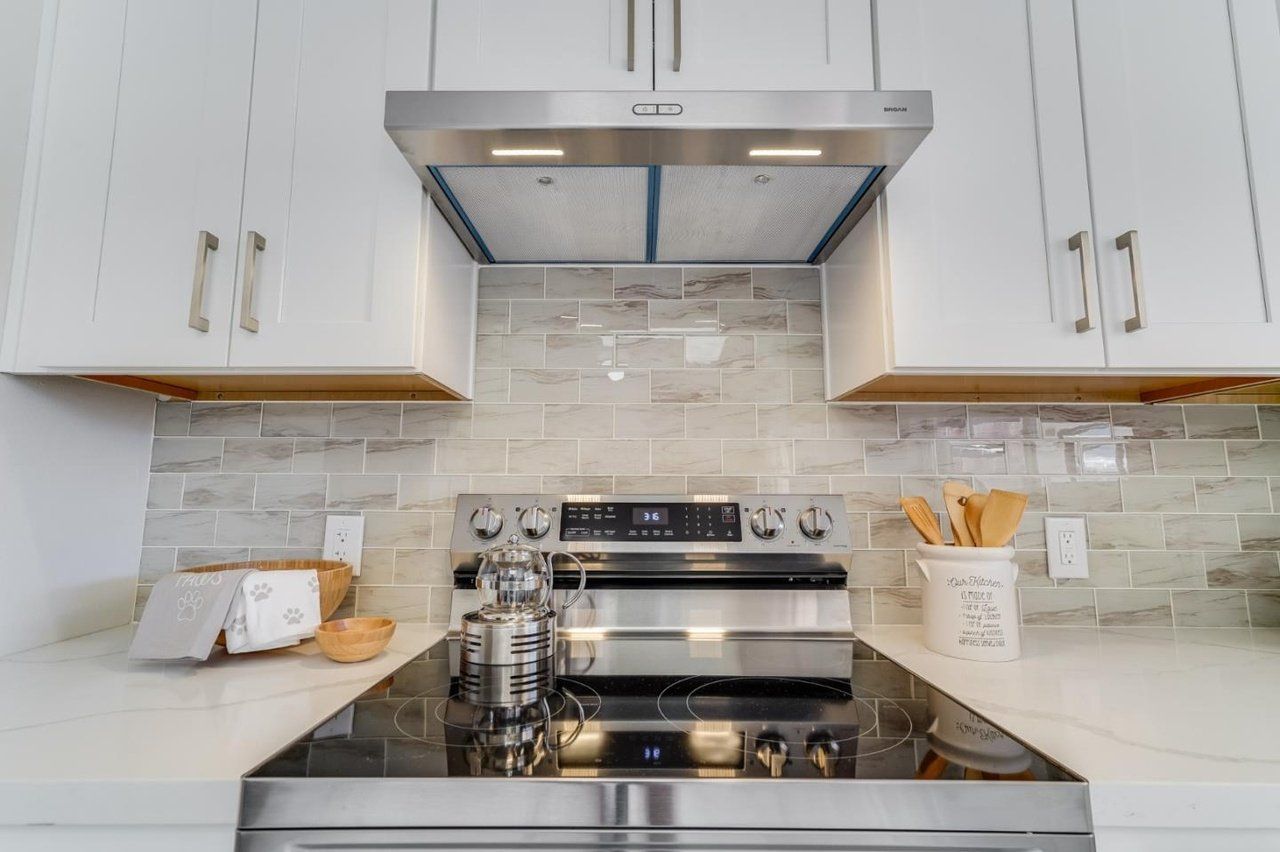 A kitchen with a stove top oven and a hood above it.