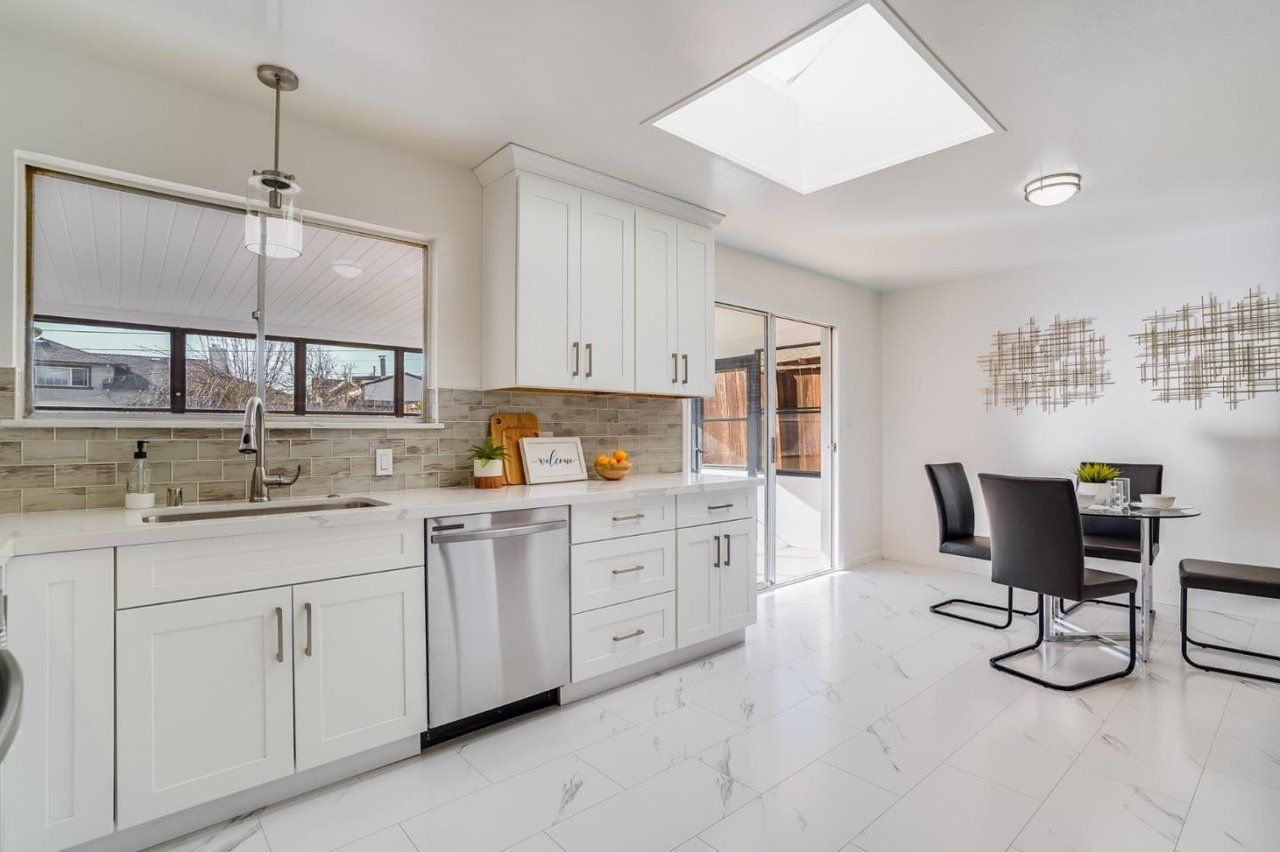 A kitchen with white cabinets , stainless steel appliances , a table and chairs.