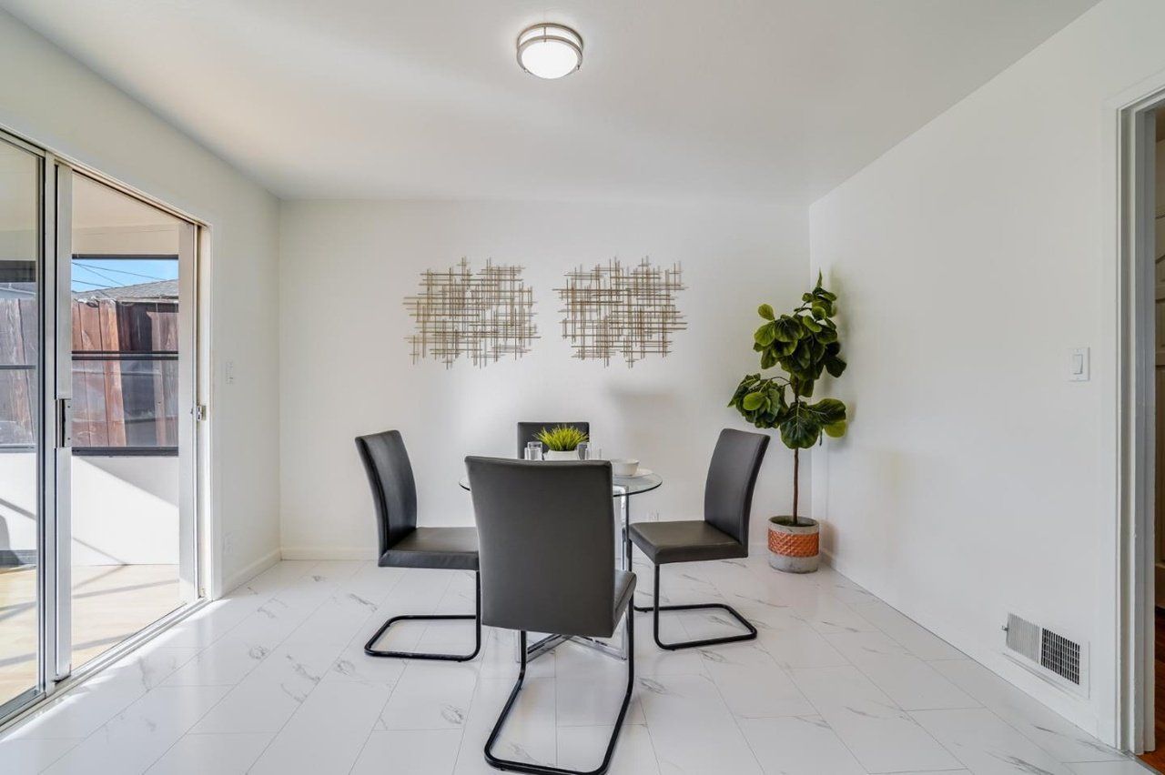 A dining room with a table and chairs and a potted plant.