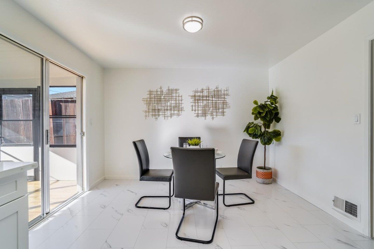 A dining room with a table and chairs and a potted plant.