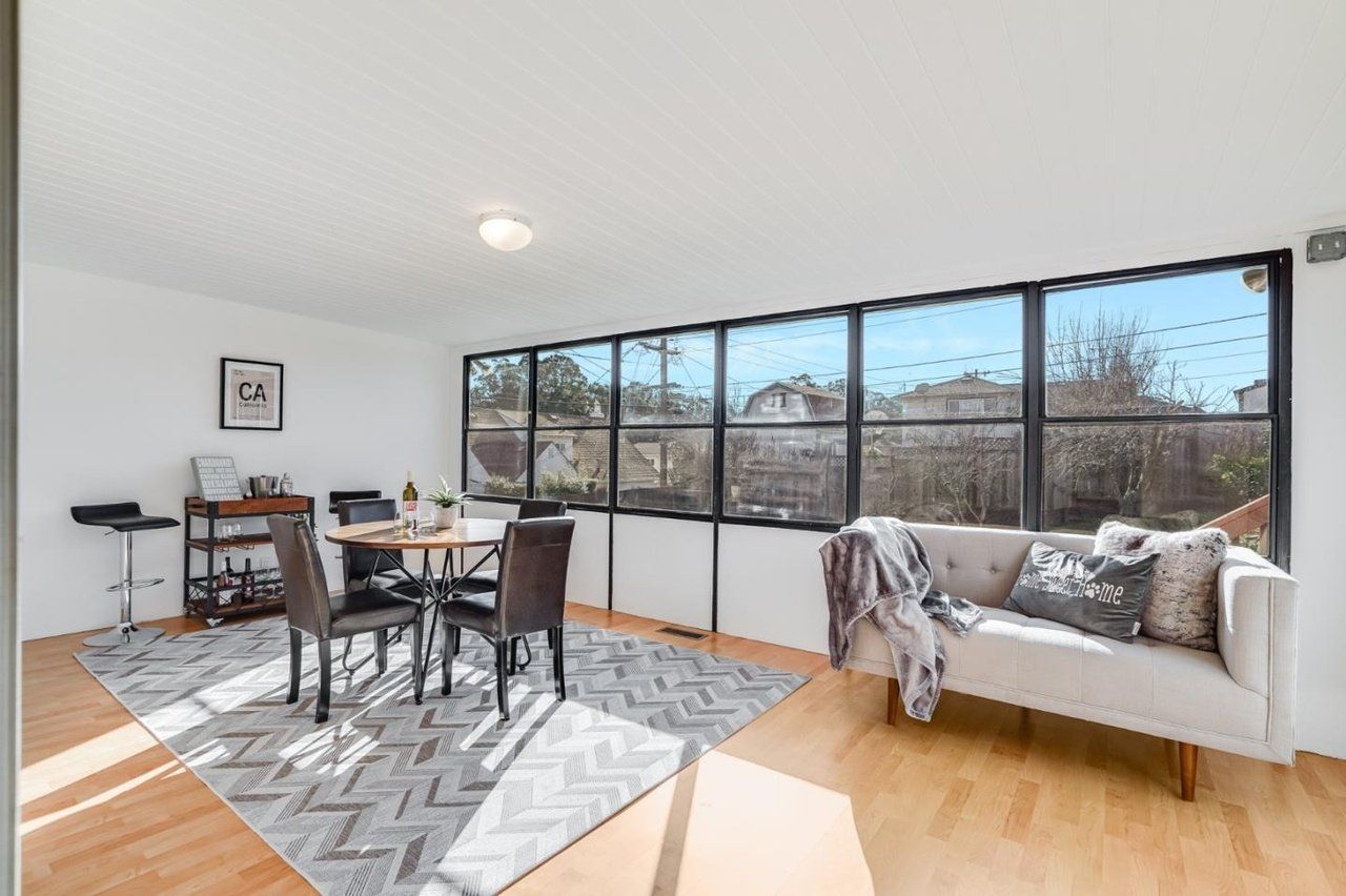 A living room with a couch , table , chairs and large windows.