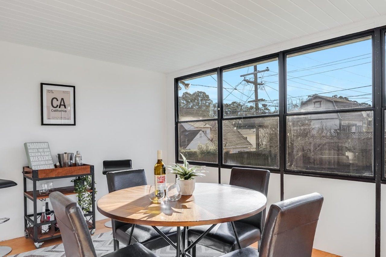 A dining room with a round table and chairs and a large window.