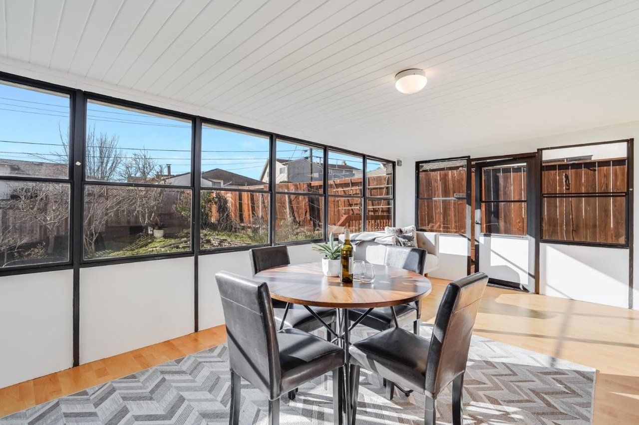 A dining room with a table and chairs and a lot of windows.