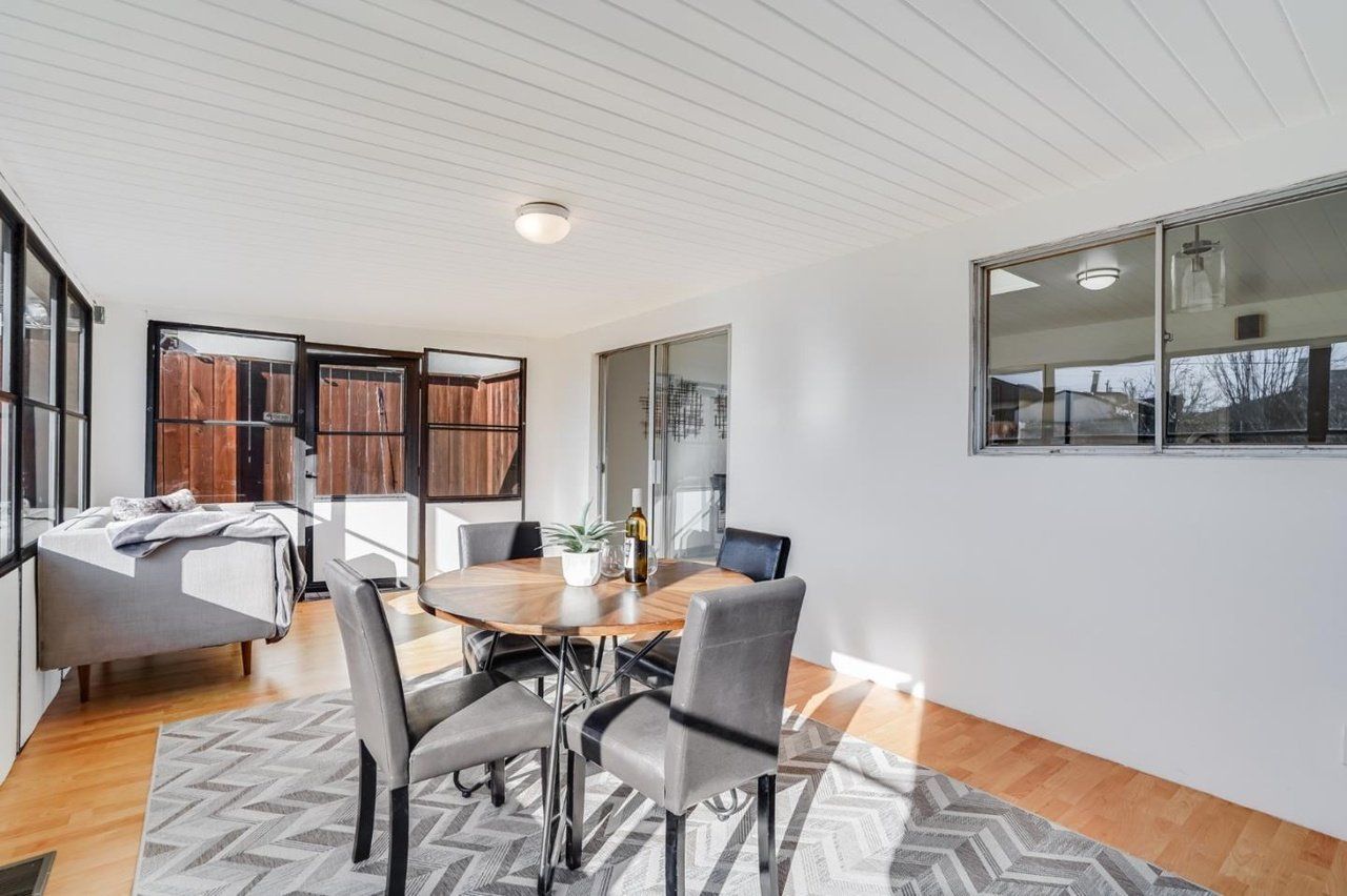 A dining room with a table and chairs and a rug.