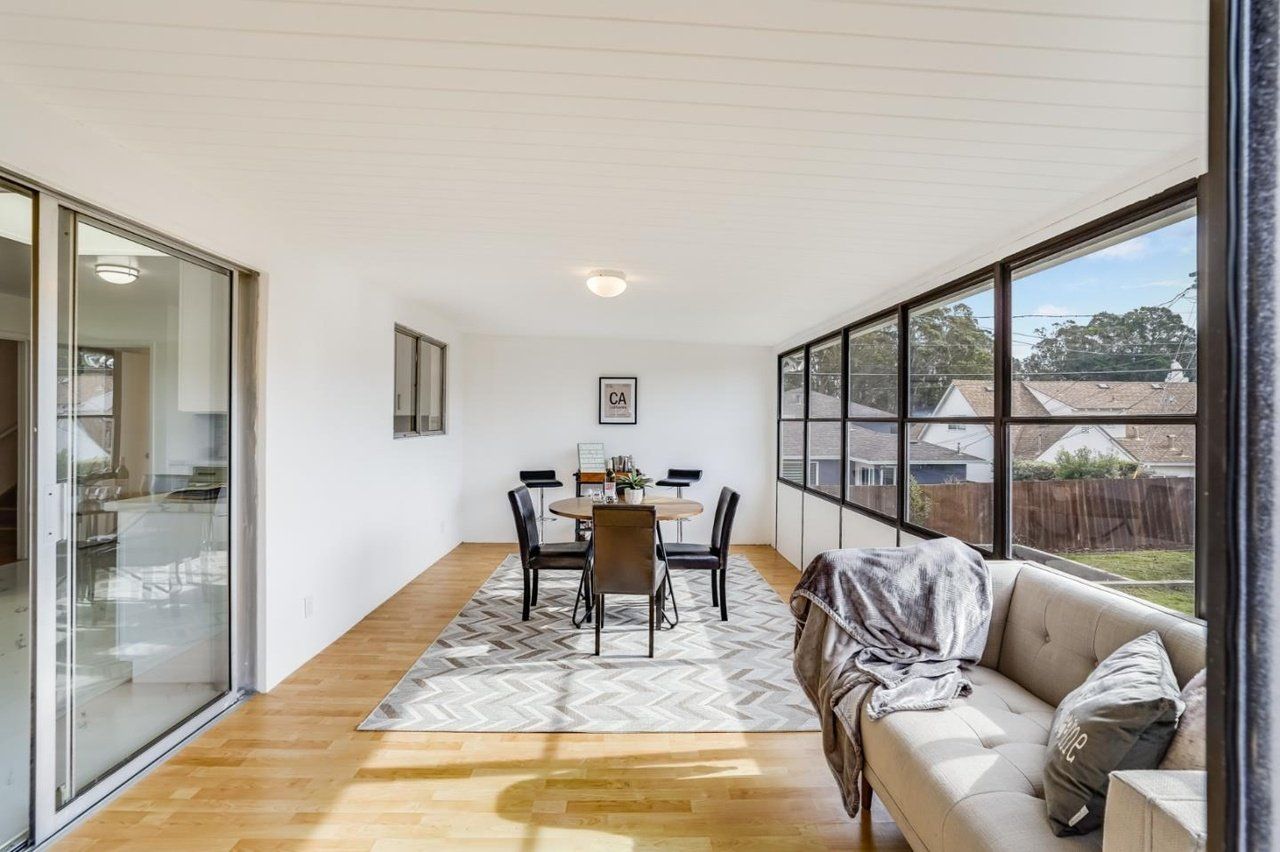 A living room with a couch , dining table and chairs.
