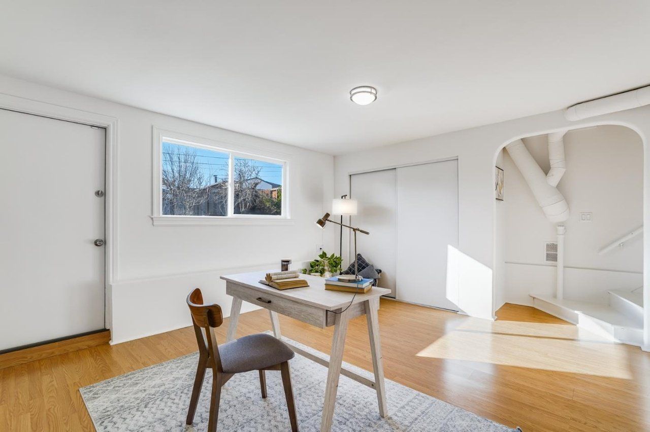 A room with a desk and chair in it and a window.