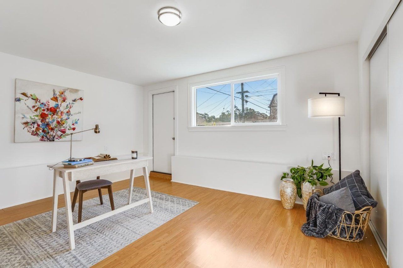 A room with a desk , chair , lamp and window.