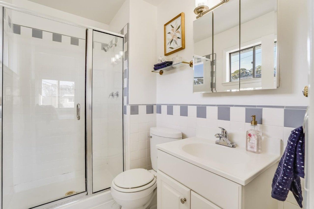 A bathroom with a toilet , sink , shower and mirror.