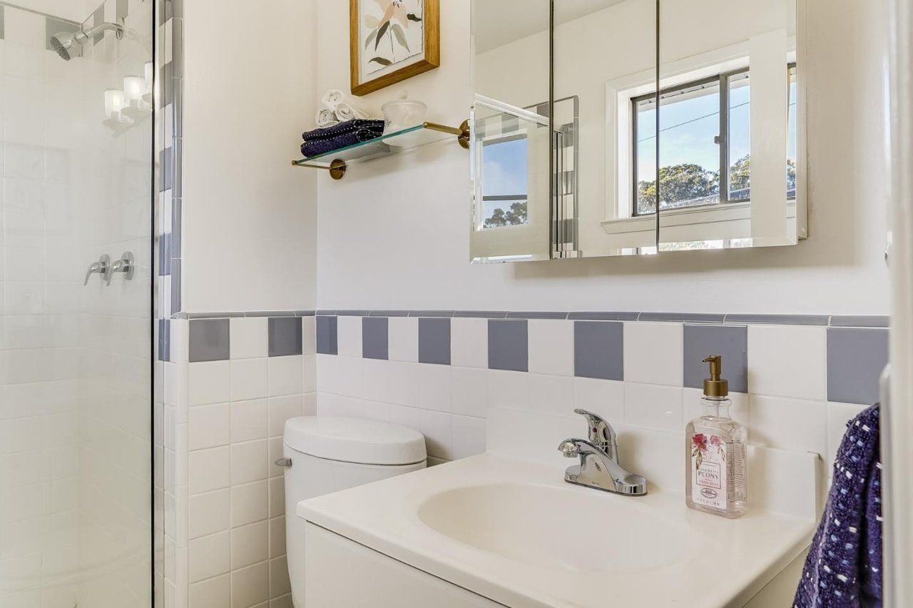 A bathroom with a toilet , sink , mirror and shower.