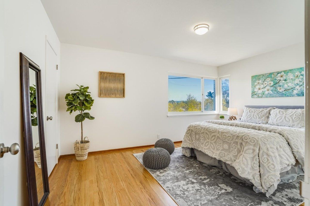 A bedroom with a large bed , a mirror and a window.