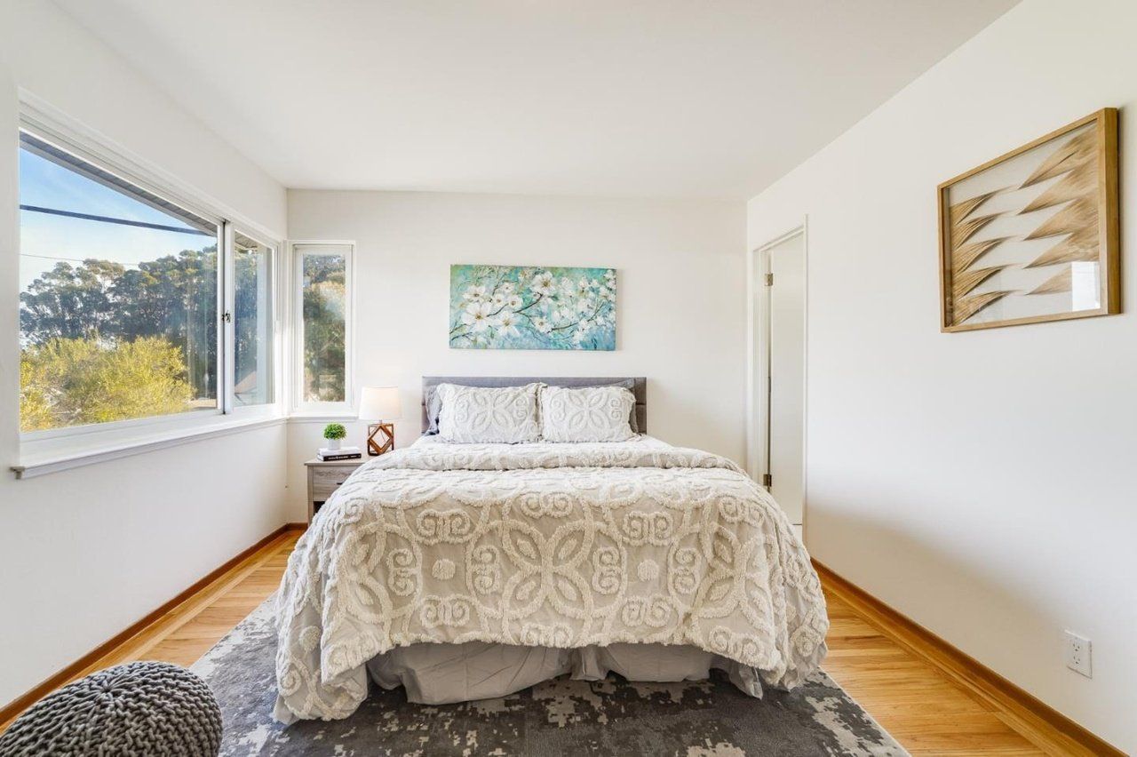 A bedroom with a bed , rug and window.