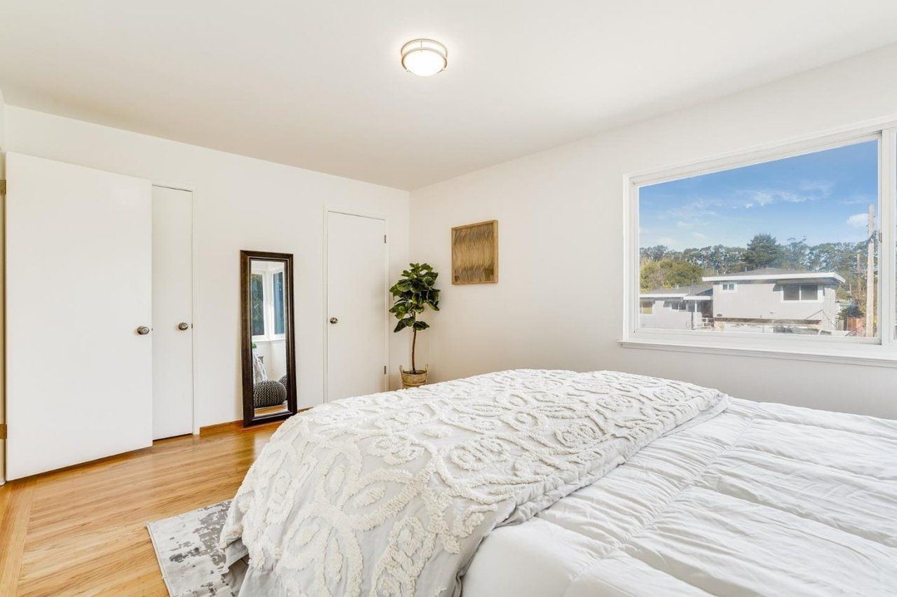 A bedroom with two beds , a mirror , and a window.