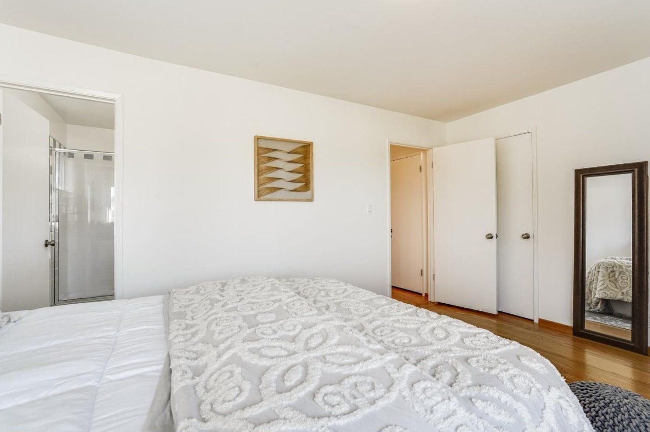 A bedroom with a large bed and a mirror.