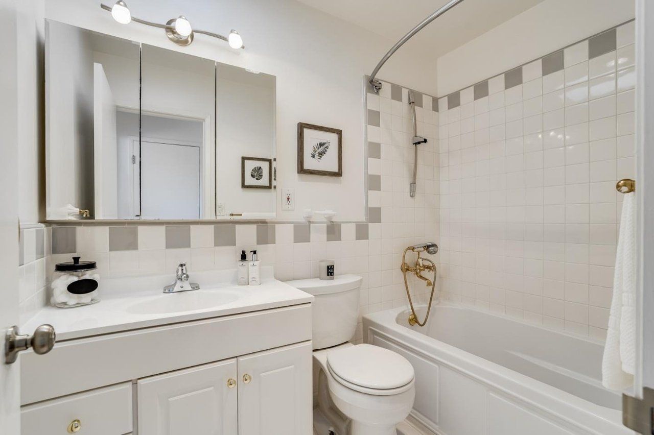 A bathroom with a toilet , sink , tub and mirror.