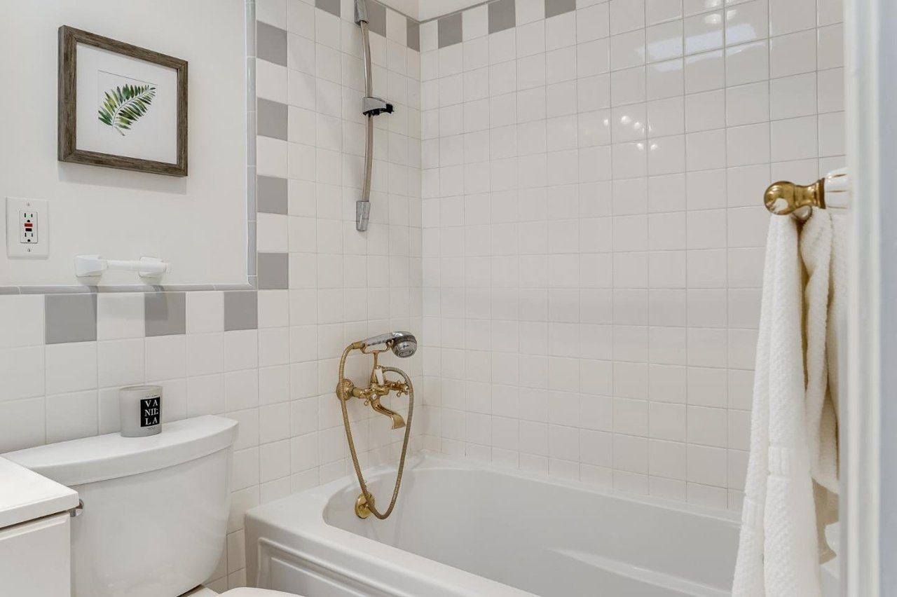 A bathroom with a toilet , tub , shower and picture on the wall.