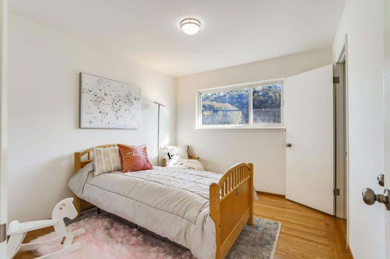 A bedroom with a bed , rug , window and door.
