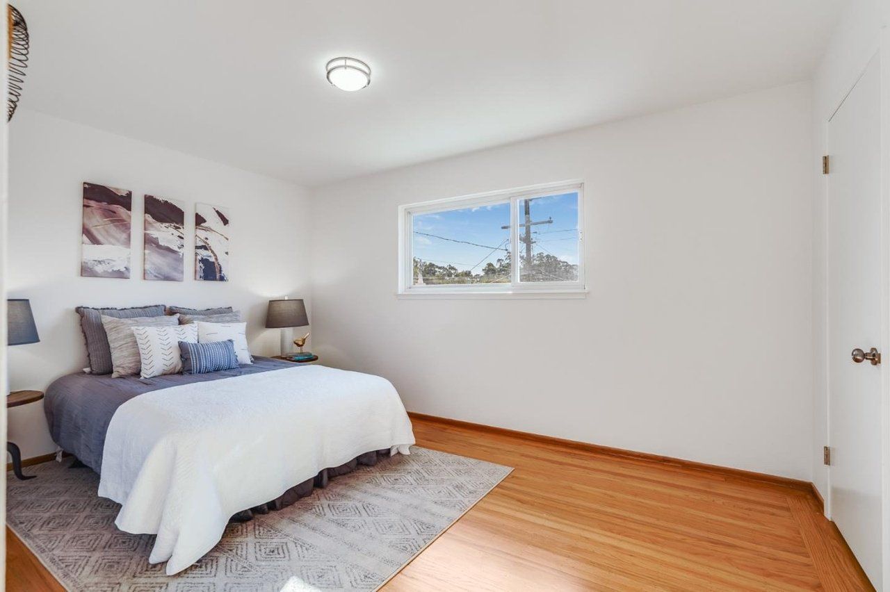 A bedroom with a bed , two windows and a rug.