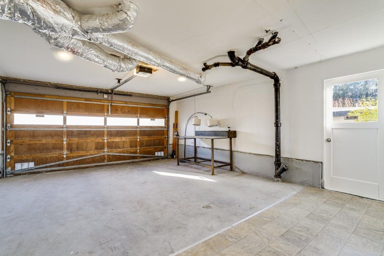 An empty garage with a garage door open and a table.