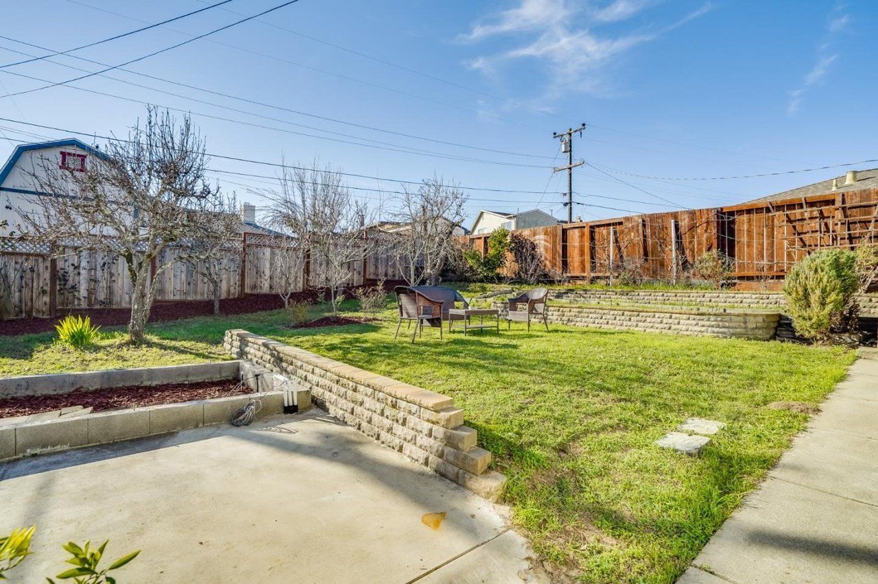 A backyard with a wooden fence and a concrete walkway.