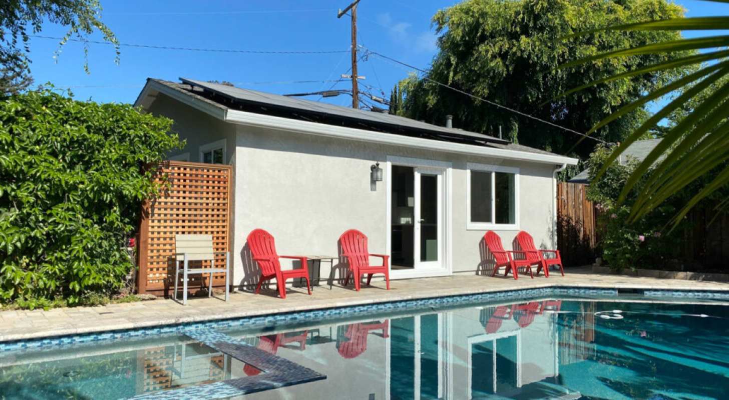 A small house with a swimming pool in front of it.