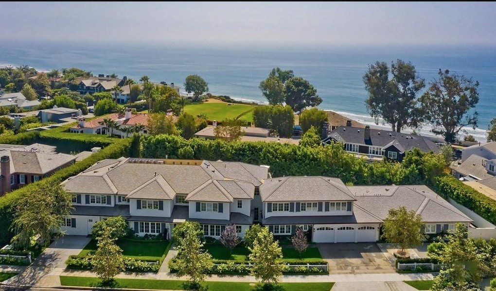 An aerial view of a large house with the ocean in the background
