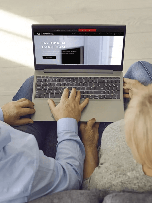 A man and a woman are sitting on a couch using a laptop computer.