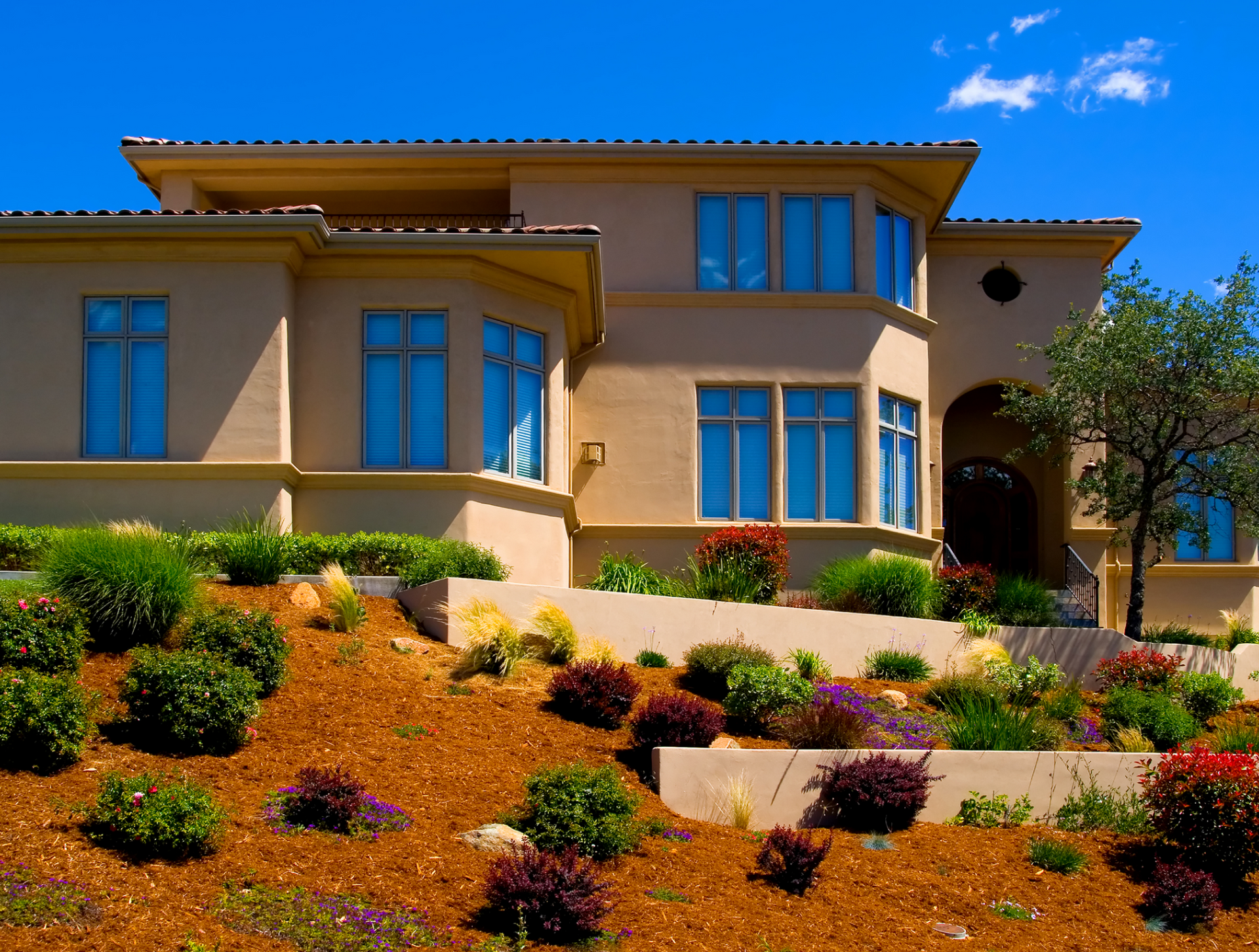 A large house sits on top of a lush green hillside