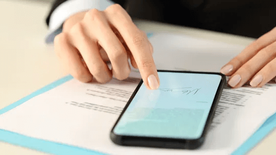 A woman is using a smart phone on a piece of paper.