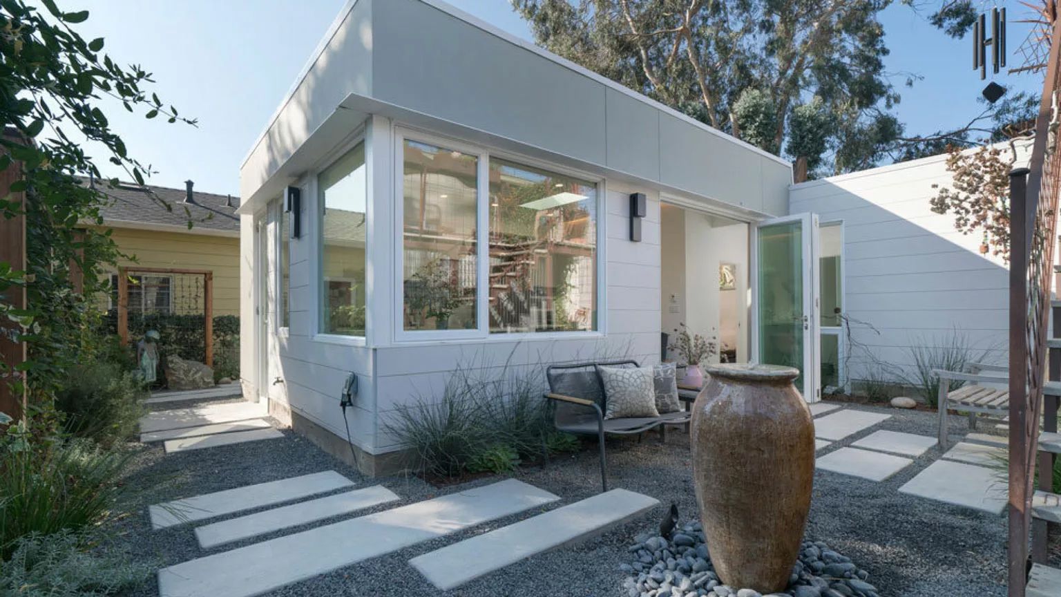 A white house with a large vase in front of it.