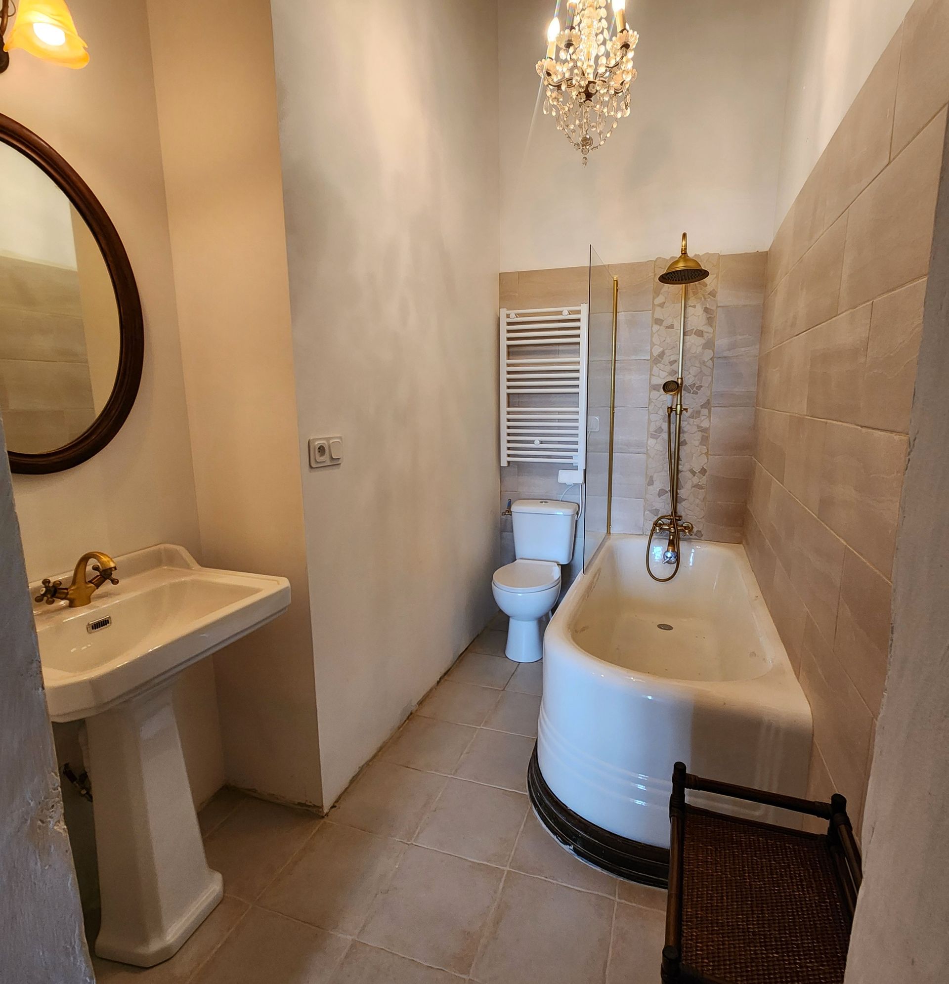 Une salle de bains de style vintage avec un lavabo sur pied et une baignoire avec pommeau de douche.